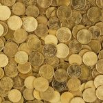 A close-up shot of Euro coins scattered in a pile, showcasing a rich golden texture.