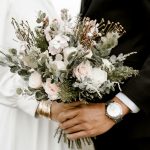 Close-up of a wedding bouquet held by bride and groom, showcasing romance and elegance.