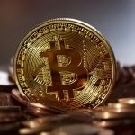 Close-up of a digital cryptocurrency Bitcoin coin placed on a pile of coins.