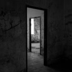 Dark, abandoned building interior with eerie shadows and graffiti-covered walls.